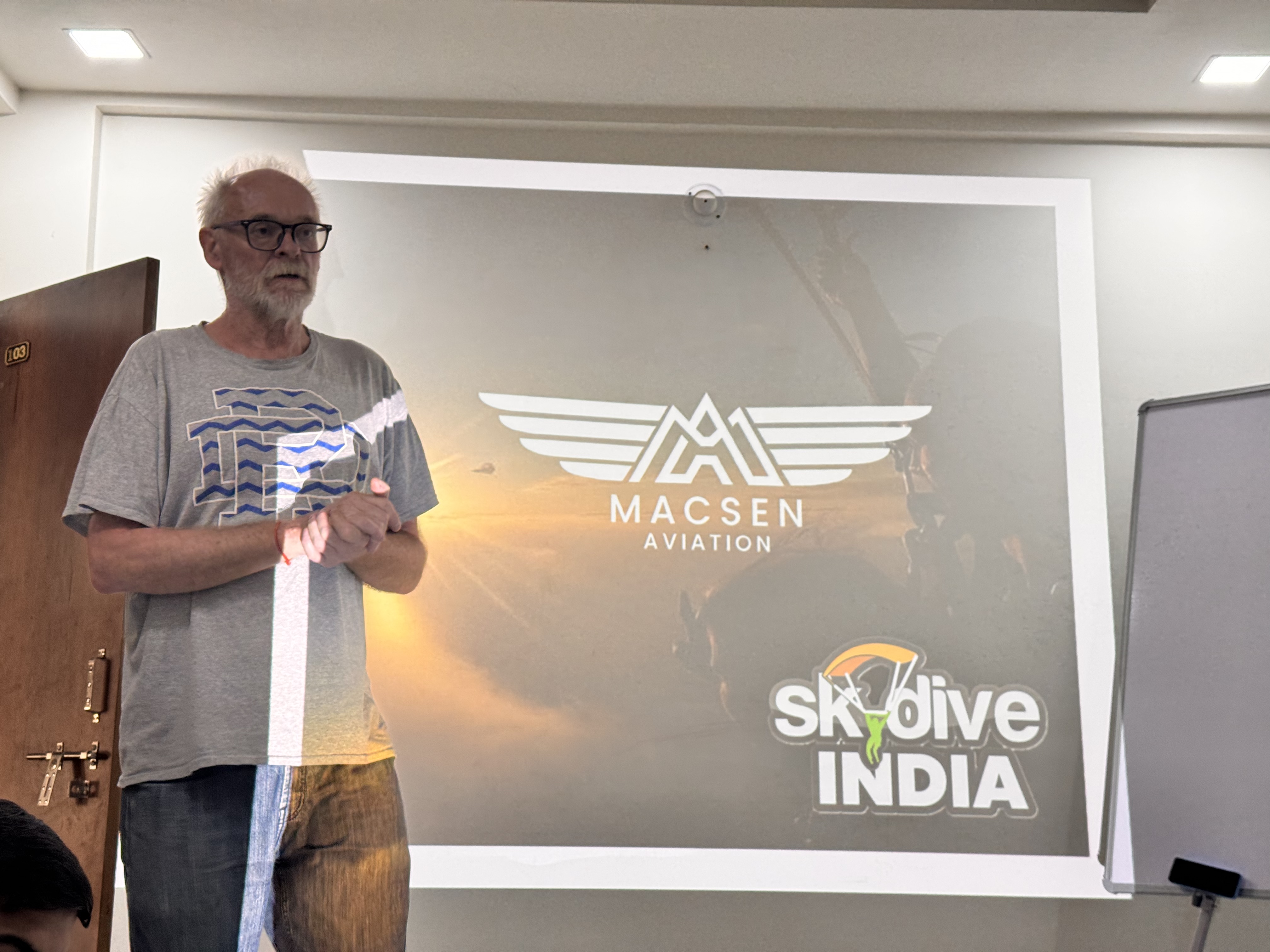 Instructor giving a safety briefing in front of a Skydive India screen