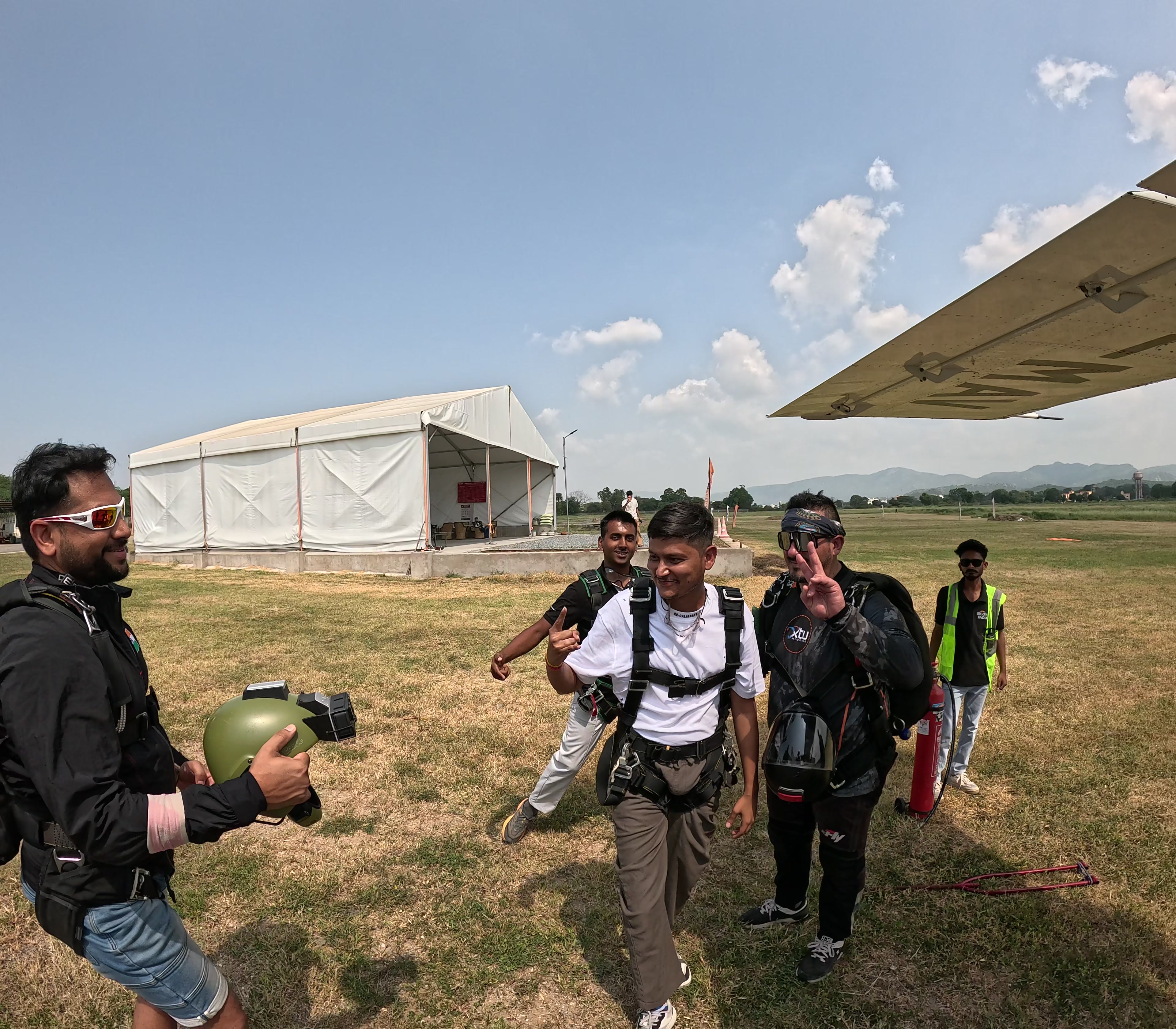 Tandem customers and instructors walking across the Mount Abu airfield to the plane