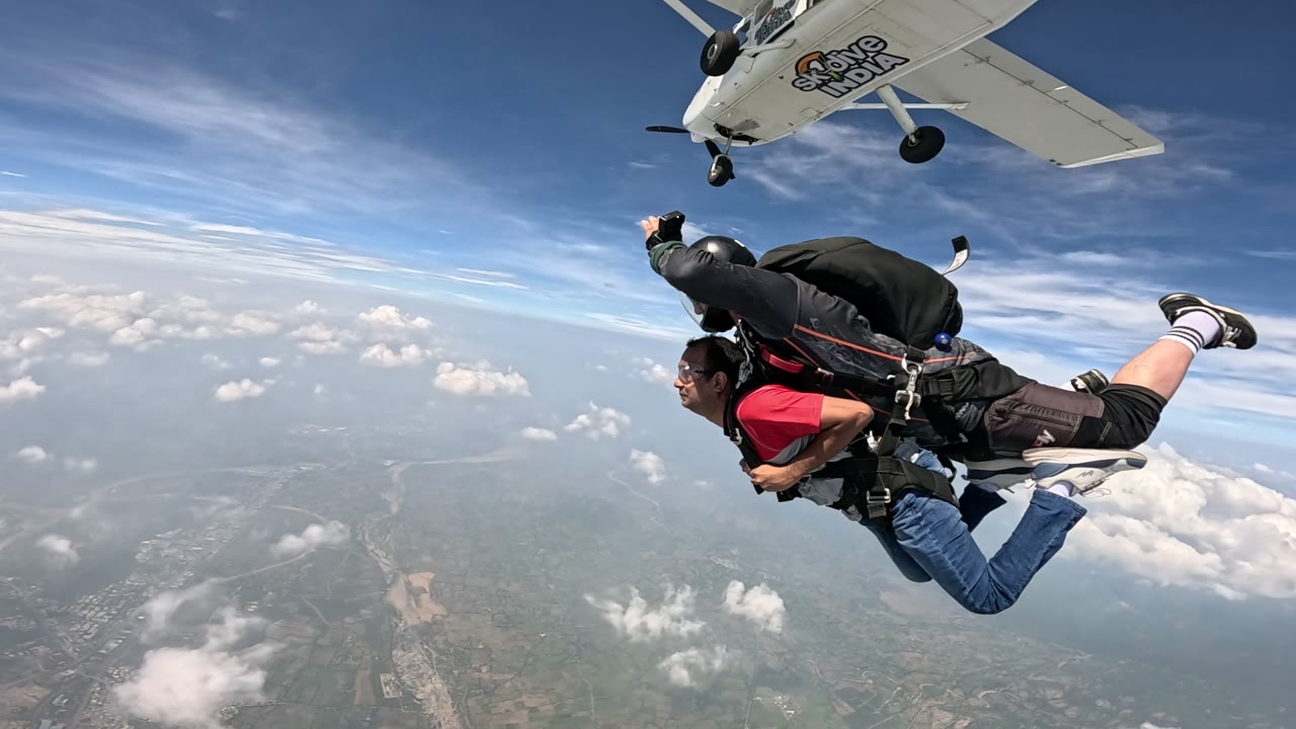 Tandem skydiver and instructor exiting an aircraft above Mount Abu