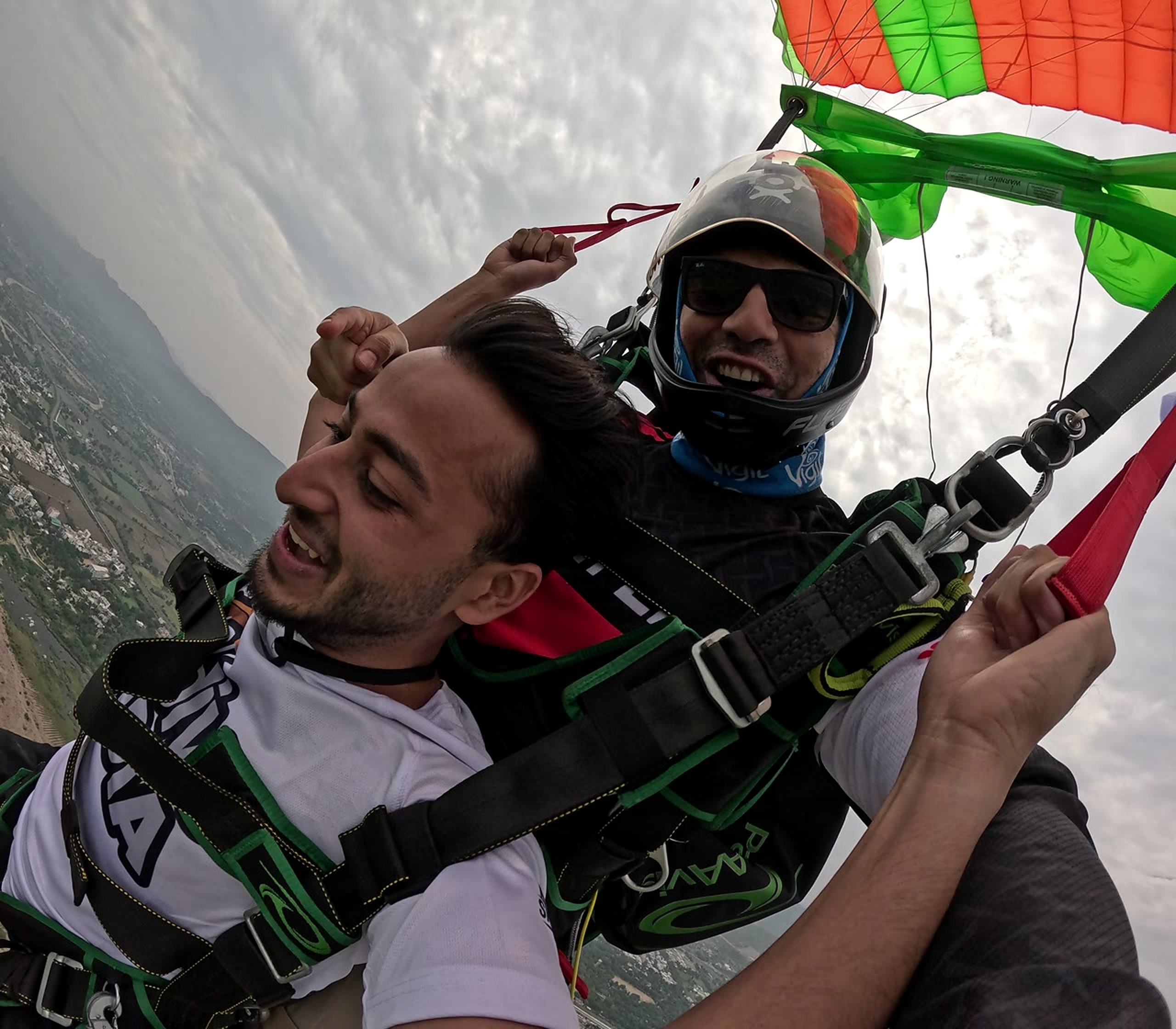 Tandem passenger and instructor flying under a colorful parachute
